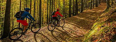 Cycling mountain biker couple on cycle trail in autumn forest