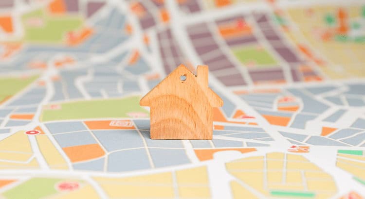 Header-Image-GettyImages-2213672932-original - Best Pittsburgh Homes Wooden house model placed on a colorful map, symbolizing real estate or finding a home